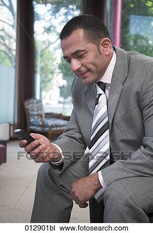 Stock Image - content looking businessman checking his mobile phone. Fotosearch