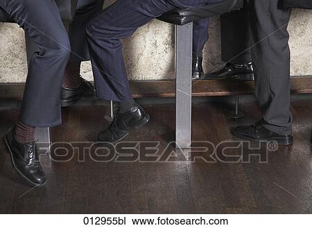 Stock Image - detail of three businessmen sitting at the bar. Fotosearch