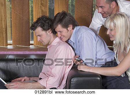 Stock Image - four friends looking at screen of notebook computer . Fotosearch