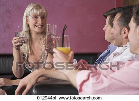 Stock Image - four friends raising their glasses in bar. Fotosearch