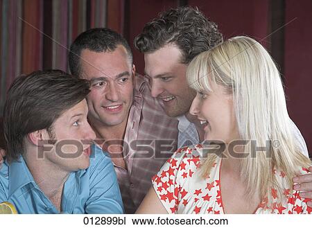 Stock Image - group of four friends talking in nightclub. Fotosearch