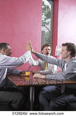 Stock Image - group of friends doing high five in restaurant. Fotosearch