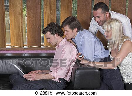 Stock Image - group watching their friend working with laptop computer. Fotosearch