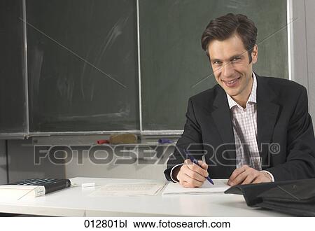 Stock Image - portrait of teacher doing corrections in classroom. Fotosearch