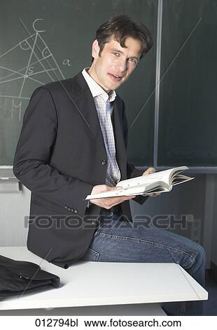 portrait of teacher sitting on table in classroom holding textbook View Large Photo Image Stock Image - portrait of teacher sitting on table in classroom holding textbook. Fotosearch