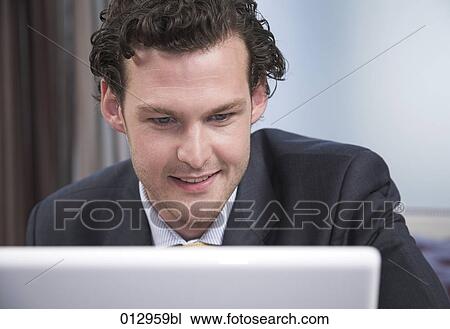portrait of young businessman looking at the screen of his notebook View Large Photo Image Stock Image - portrait of young businessman looking at the screen of his notebook. Fotosearch