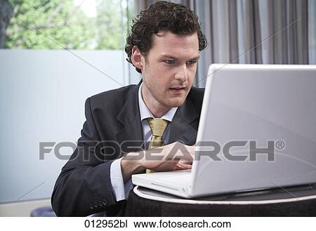 Stock Image - portrait of young businessman working with laptop computer. Fotosearch