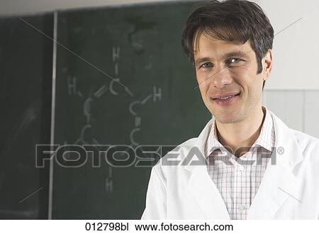 Stock Image - smiling scientis in front of blackboard with chemical formula. Fotosearch