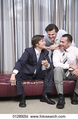 Stock Image - three businessmen enjoying news received over cellular phone. Fotosearch