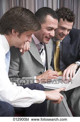Stock Image - three businessmen sitting in front of laptop computer. Fotosearch