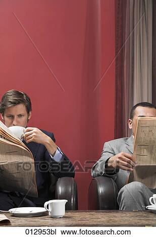 Stock Image - two businessmen reading newspapers and drinking coffee. Fotosearch