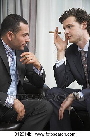 Stock Image - two businessmen sitting face to face and having a conversation. Fotosearch