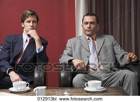 Stock Image - two worried looking businessmen during a coffee break. Fotosearch