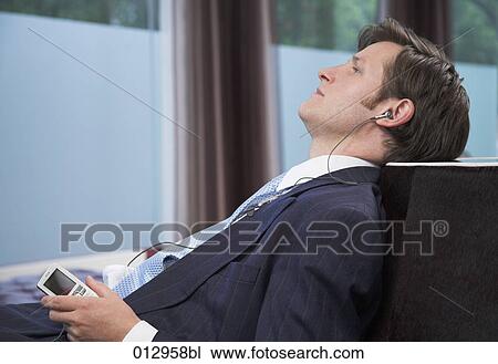 young businessman relaxing and listening to music on ipod View Large Photo Image Stock Image - young businessman relaxing and listening to music on ipod. Fotosearch