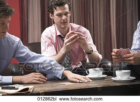 Stock Image - young gambler looking at his cards. Fotosearch