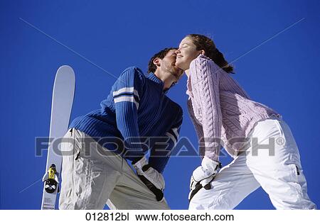 Stock Image - young man kissing woman on cheek on mountain top. Fotosearch