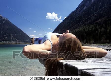 young woman relaxing on pier in Alpine landscape View Large Photo Image Stock Image - young woman relaxing on pier in Alpine landscape. Fotosearch