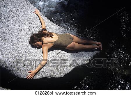 young woman sunbathing on rock View Large Photo Image Stock Image - young woman sunbathing on rock. Fotosearch