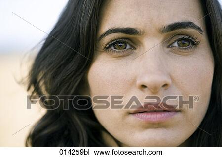 Stock Image - close-up portrait of serious looking young woman. Fotosearch