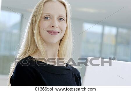 Stock Image - confidently smiling woman sitting behind her computer. Fotosearch