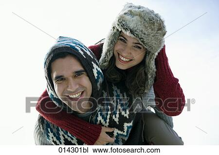 Stock Image - couple in winter clothes playing piggyback. Fotosearch