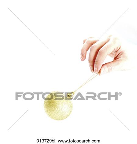 Stock Image - hand holding golden bauble. Fotosearch