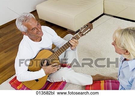 Stock Image - high angle view of mature husband playing guitar for his wife. Fotosearch