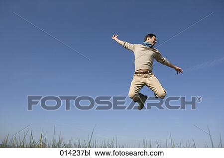 Stock Image - joyous young man doing a high jump . Fotosearch