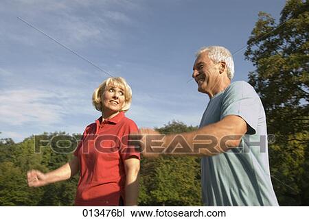 Stock Image - low angle view of couple jogging in park. Fotosearch