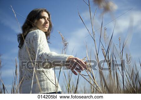 low angle view of young woman touching reeds in field View Large Photo Image Stock Image - low angle view of young woman touching reeds in field. Fotosearch