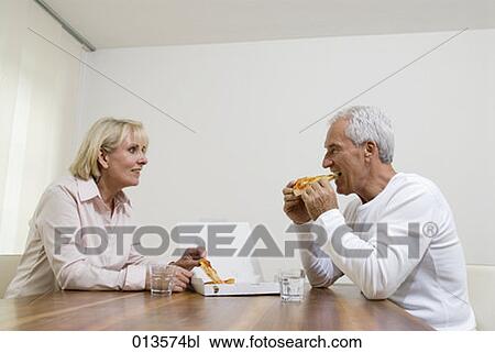 Stock Image - mature couple eating pizza together. Fotosearch