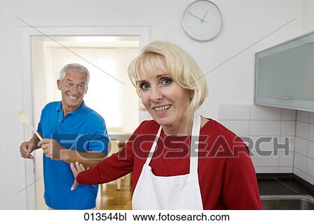 Stock Image - mature couple having fun in kitchen. Fotosearch