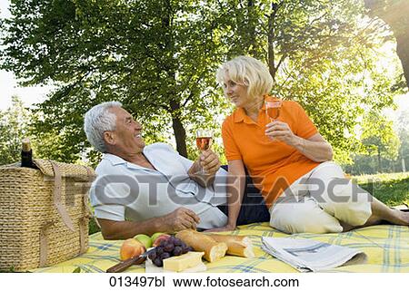 Stock Image - mature couple having picnic in park . Fotosearch