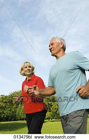 Stock Image - mature couple jogging woman looking at man. Fotosearch