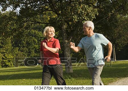 Stock Image - mature couple looking at each other while jogging in park . Fotosearch