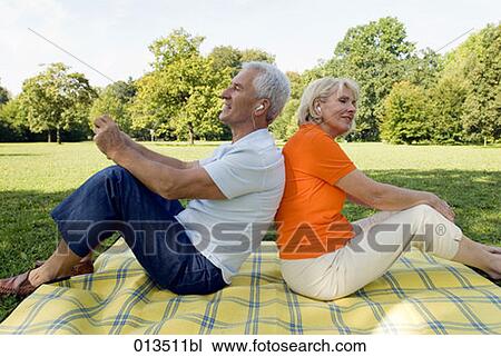 mature couple sitting back to back listening to music in park View Large Photo Image Stock Image - mature couple sitting back to back listening to music in park. Fotosearch