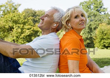 Stock Image - mature man and woman wearing earphones enjoying some music. Fotosearch