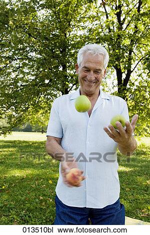 Stock Image - mature man juggling in park. Fotosearch