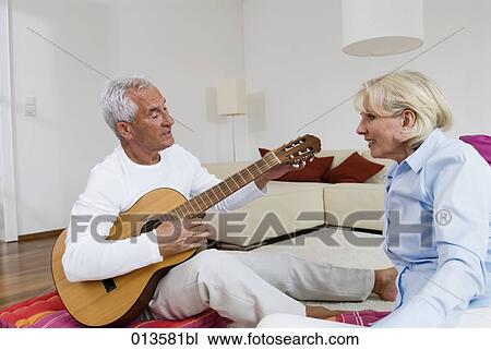 Stock Image - mature man playing guitar for his wife. Fotosearch