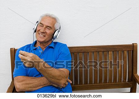 mature man sitting on bench listening to music View Large Photo Image Stock Image - mature man sitting on bench listening to music. Fotosearch
