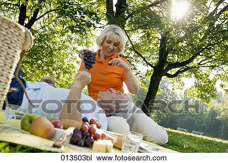 Stock Image - mature woman feeding husband with grapes. Fotosearch
