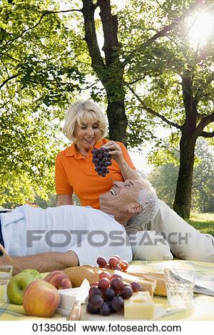 mature woman feeding man grapes at picnic in park View Large Photo Image Stock Image - mature woman feeding man grapes at picnic in park. Fotosearch