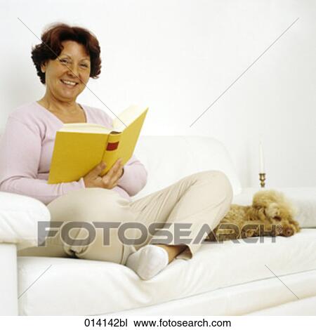 mature woman sitting on sofa reading with dog beside her View Large Photo Image Stock Image - mature woman sitting on sofa reading with dog beside her. Fotosearch
