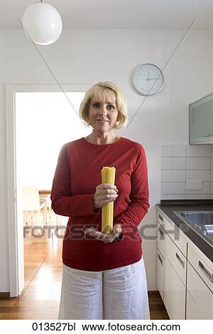 mature woman standing in kitchen holding spaghettis View Large Photo Image Stock Image - mature woman standing in kitchen holding spaghettis. Fotosearch