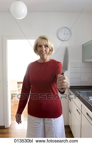 mature woman standing in kitchen holding knife View Large Photo Image Stock Image - mature woman standing in kitchen holding knife. Fotosearch