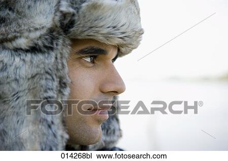 Stock Image - melancholic looking man with fur hat in profile. Fotosearch