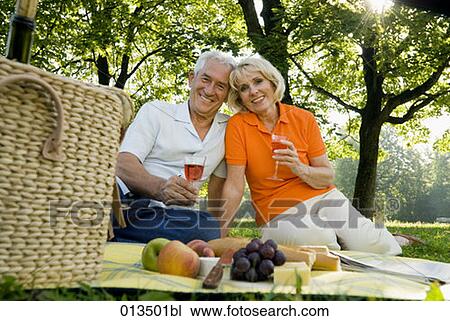 Stock Image - portrait of happy mature couple having picnic in park. Fotosearch