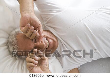 Stock Image - portrait of mature man awaking rubbing his eyes. Fotosearch