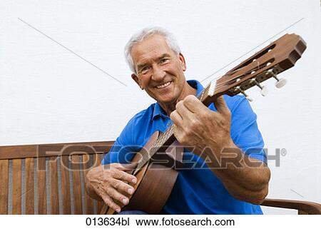 Stock Image - portrait of mature man playing guitar. Fotosearch