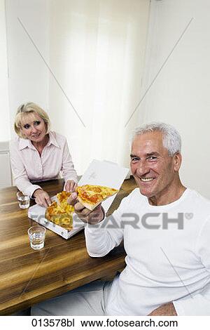 Stock Image - portrait of mature man sharing pizza with his wife. Fotosearch